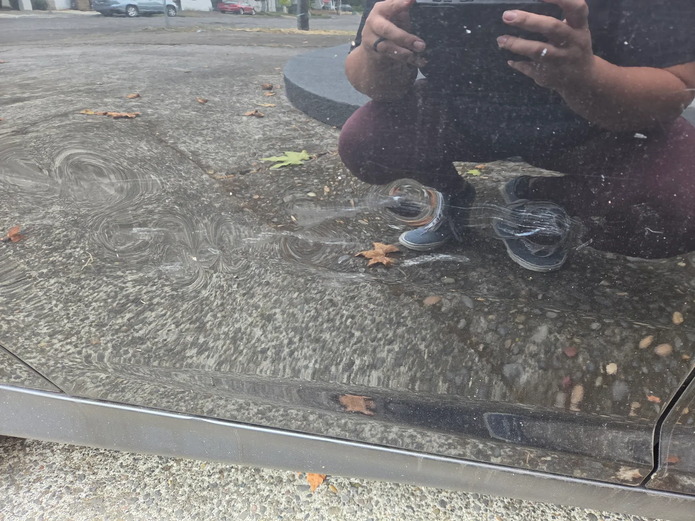 Close-up view of scratches and surface distortion on the black Ford Focus door panel before repair.